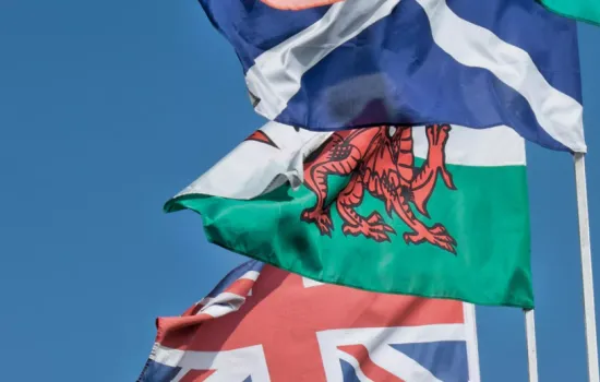 An image of the Welsh dragon flag, the British Union Jack and the Scottish flag flying against a blue sky.