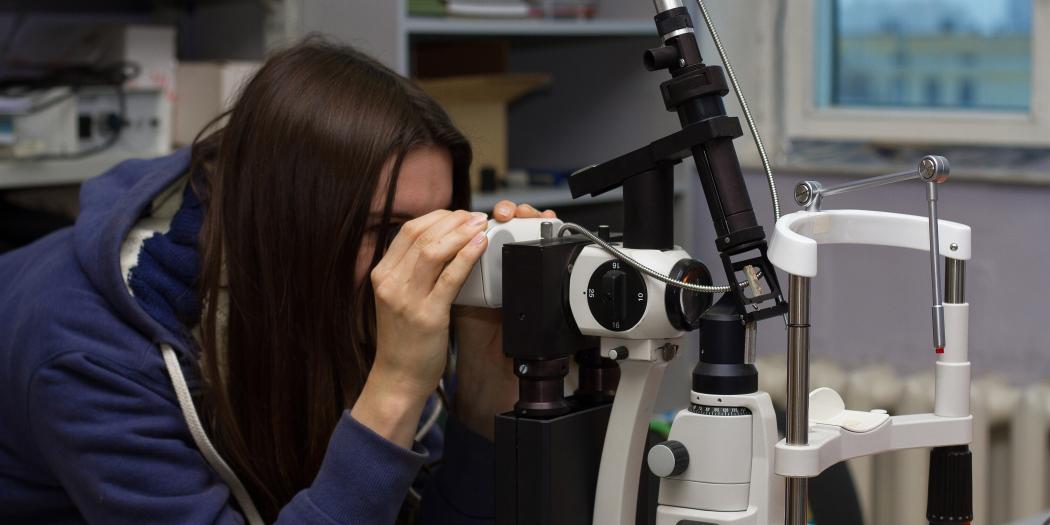 A female student looks through a microscope.