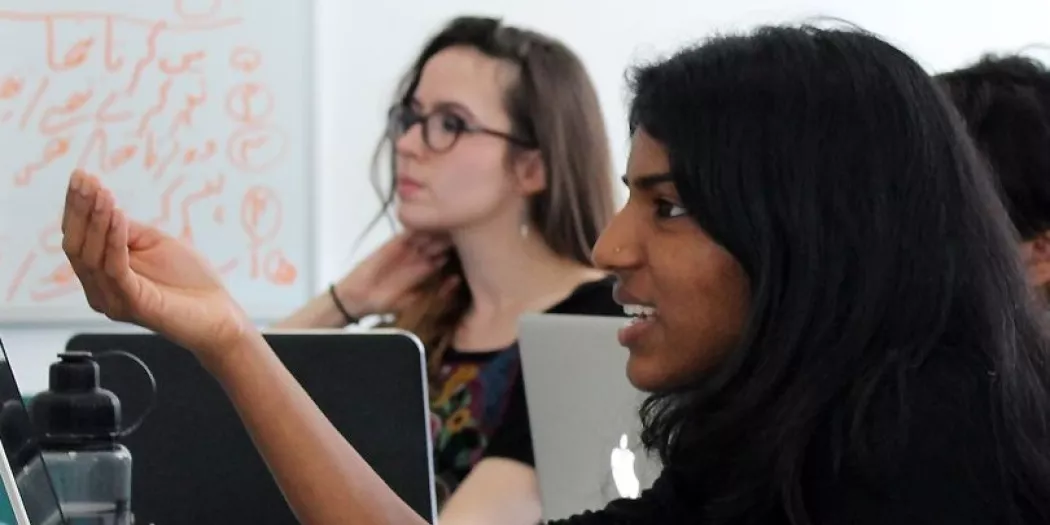 A female student gestures during a discussion in a classroom.