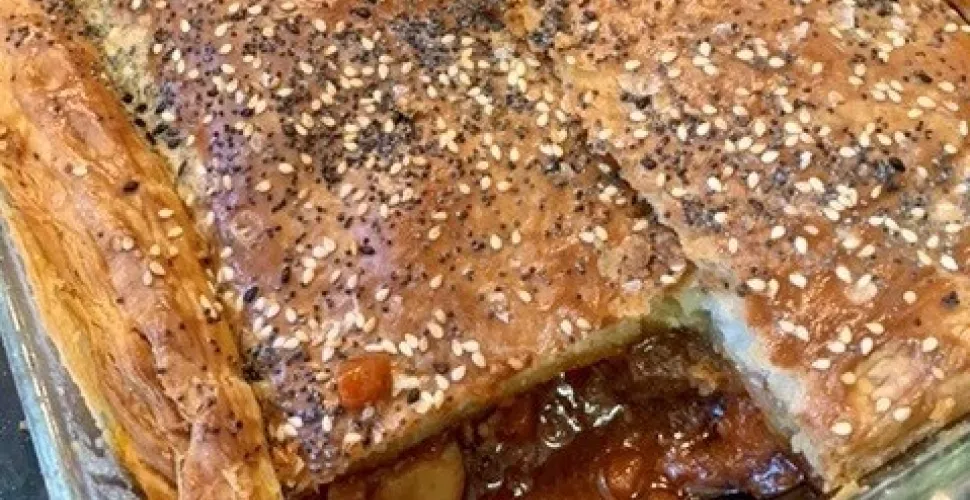 A finished beef and mushroom pie with a slice taken out.
