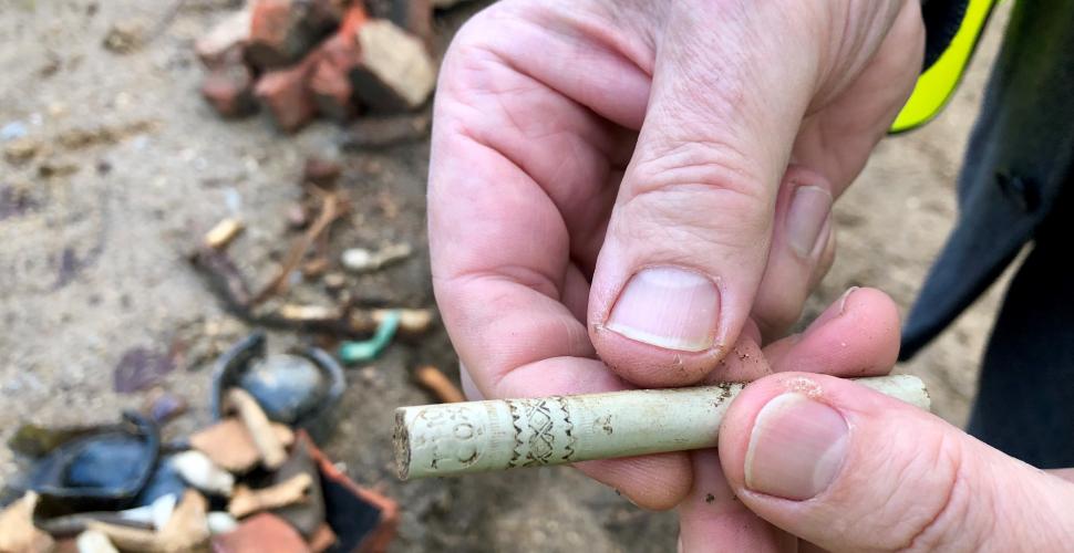 A member of Oxford Archaeology holds a clay pipe stem uncovered during the archaeological work on the site.