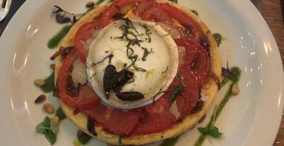 A plated goats cheese tart with garnish.