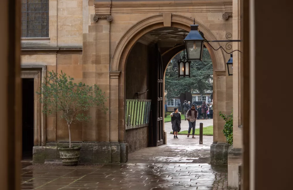 A view of the Trinity College chapel arch, with two students approaching the arch in the distance.
