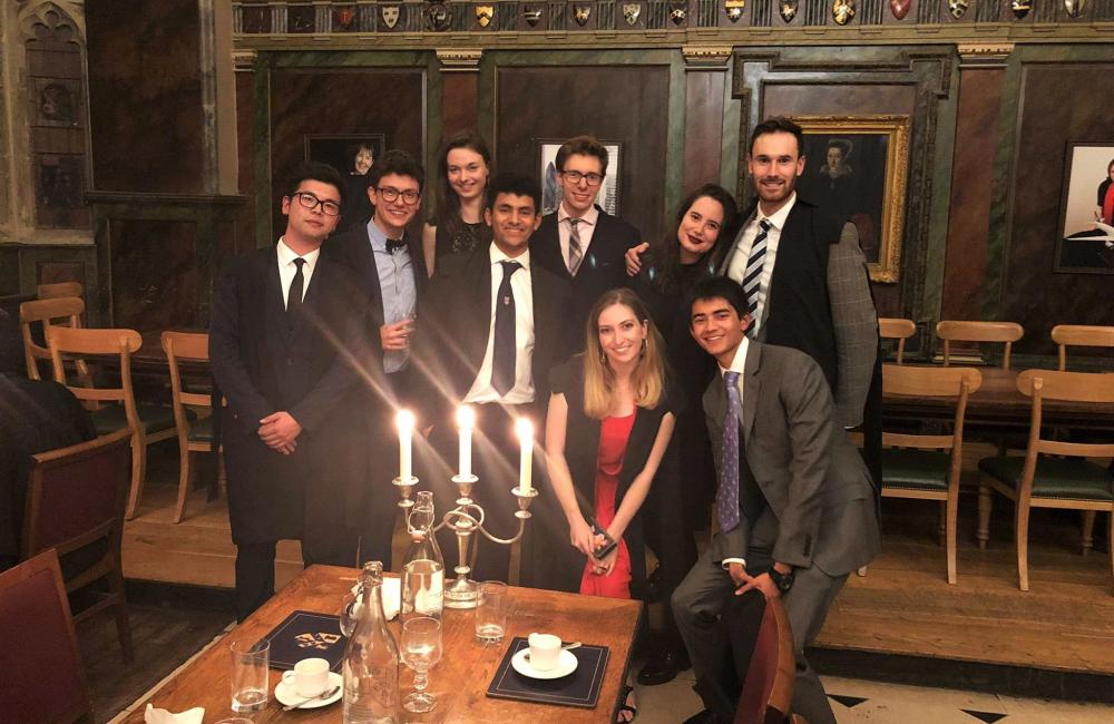 A group of Trinity College MCR students pose at formal hall in the dining hall.