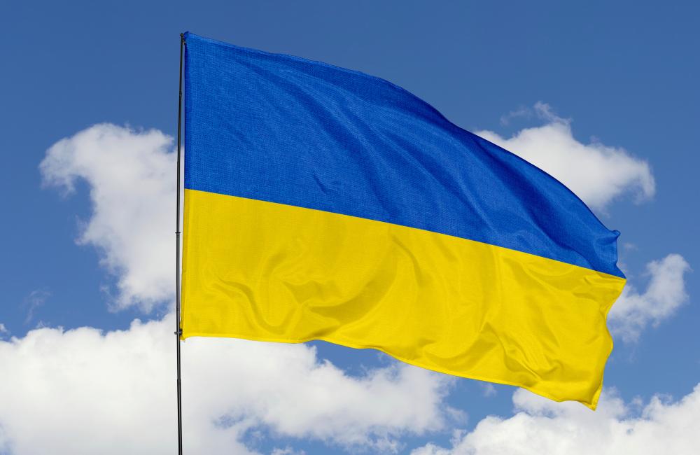 The Ukrainian flag flies on a sunny day against a blue sky with white clouds.