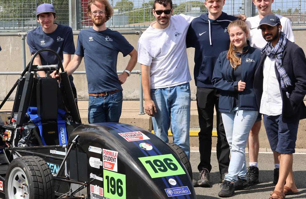 A group of Oxford students from the Oxford Racing team stand next to their electric vehicle at the Formula Student competition.