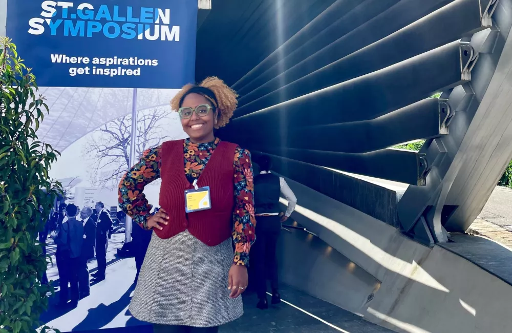 Luisa Costa stands in front of a sign for the St Gallen Symposium.