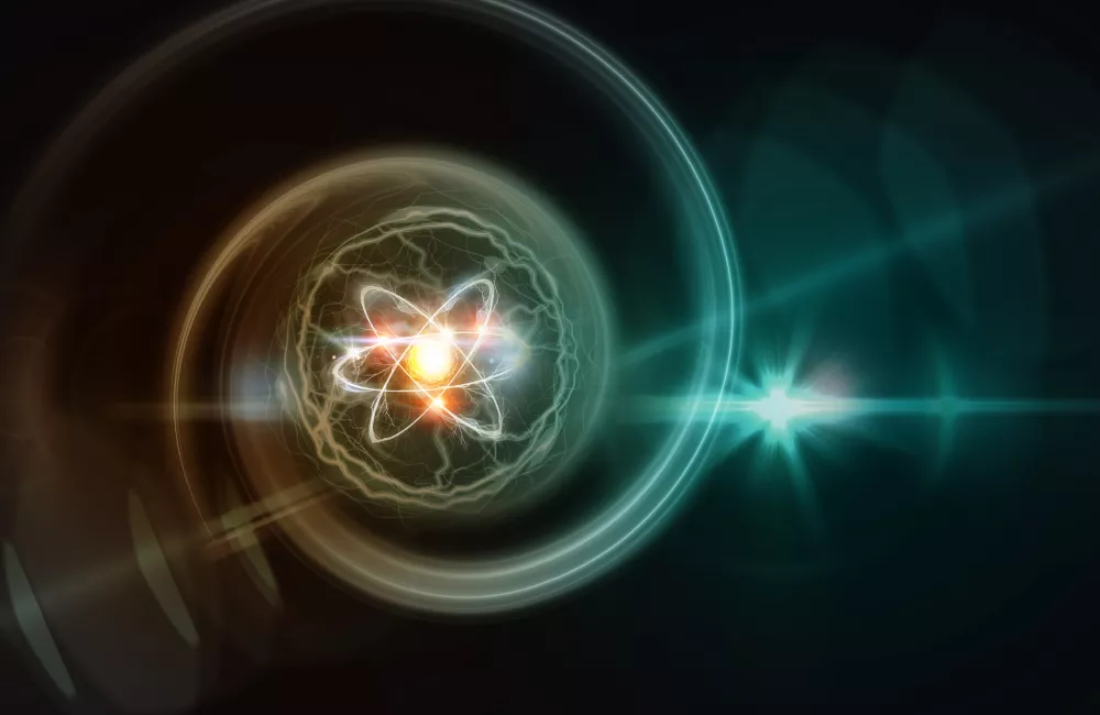 Digital illustration of an atom with glowing electrons orbiting a bright nucleus, surrounded by swirling energy and light flares on a dark background,