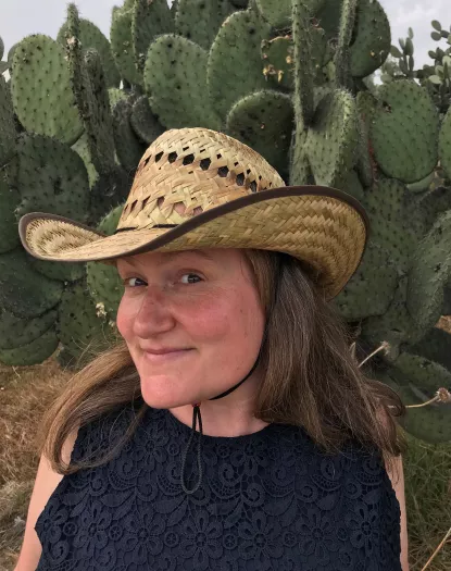Kate Burtonwood in a straw cowboy hat with cacti in the background.