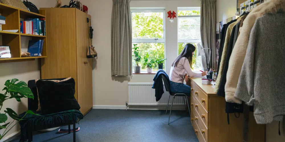 A student at her desk in a shared bedroom set.