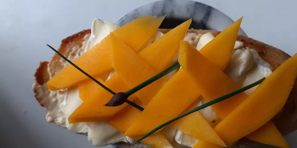 A bruschetta with mango and brie topping.