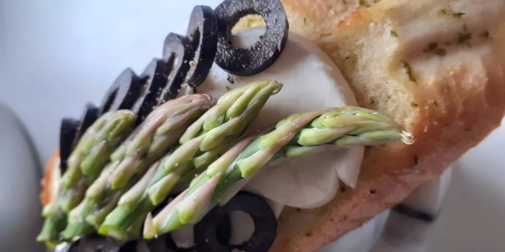 A bruschetta with olive and asparagus topping.