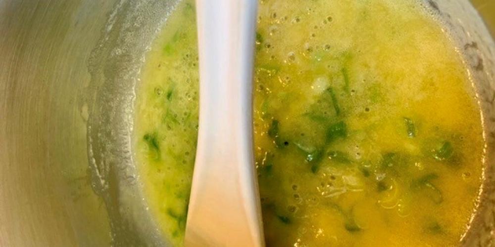 A melted butter and herb mixture being stirred.