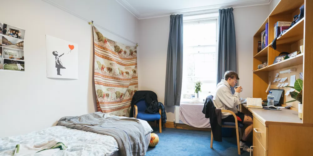 A first-year student studies at a desk in his room.