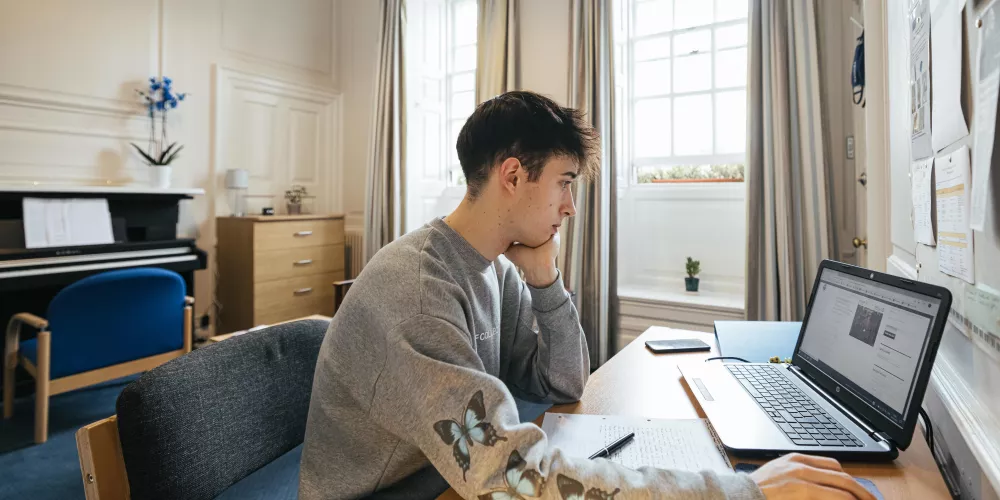 A first-year student in front of his computer in his study bedroom.