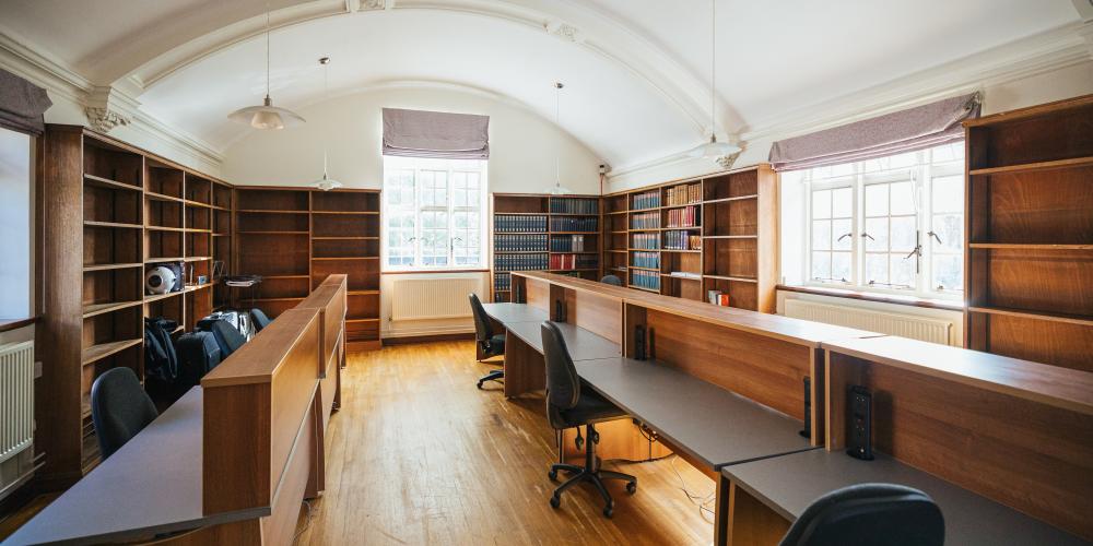 The study library in the Old Nunnery with empty desk spaces and light shining in the windows.