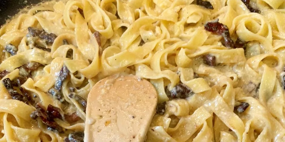 A pan of mixed carbonara being stirred.