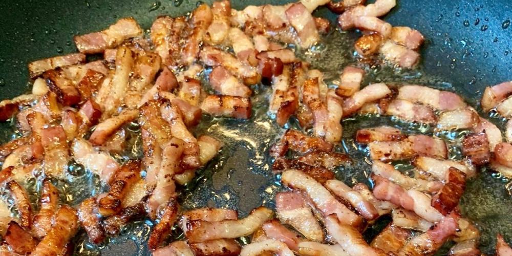 A pan of bacon cooking in close-up.