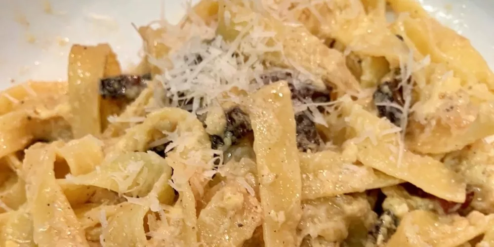 A bowl of garnished pasta carbonara.