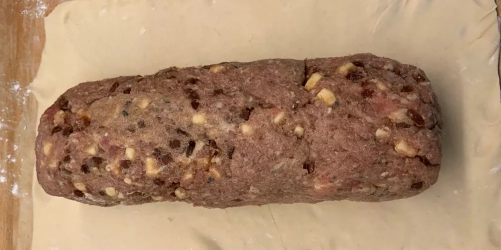 A sausage meat on a rolled-out puff pastry sheet.