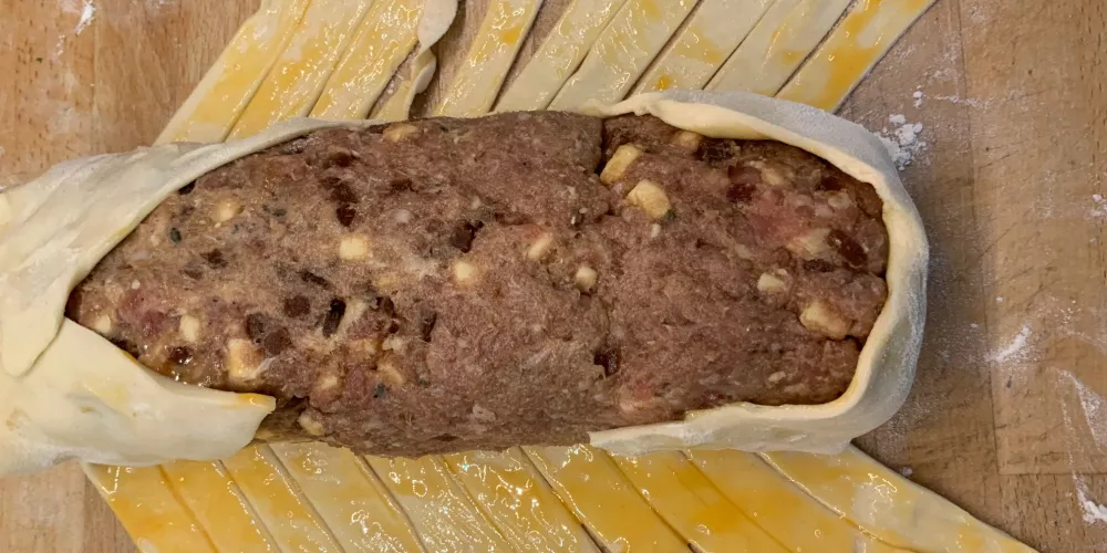 Sausage meat wrapped in puff pastry cut thinly in diagonal slices and egg washed.