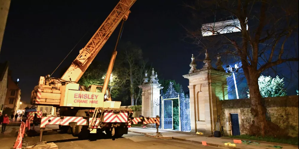 A night view of a giant crane lifting building materials over the Stuart Gate.