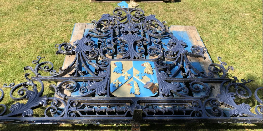The wrought iron Stuart Gate lies on the grass in college.