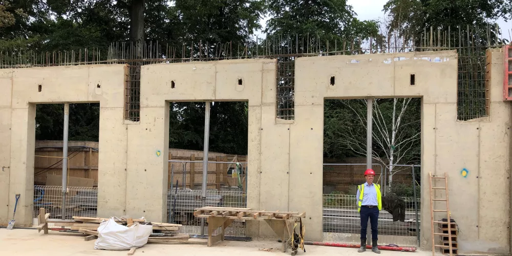 A Trinity staff member on a site visit stands in front of what will be the large windows in the Levine Building cafe.