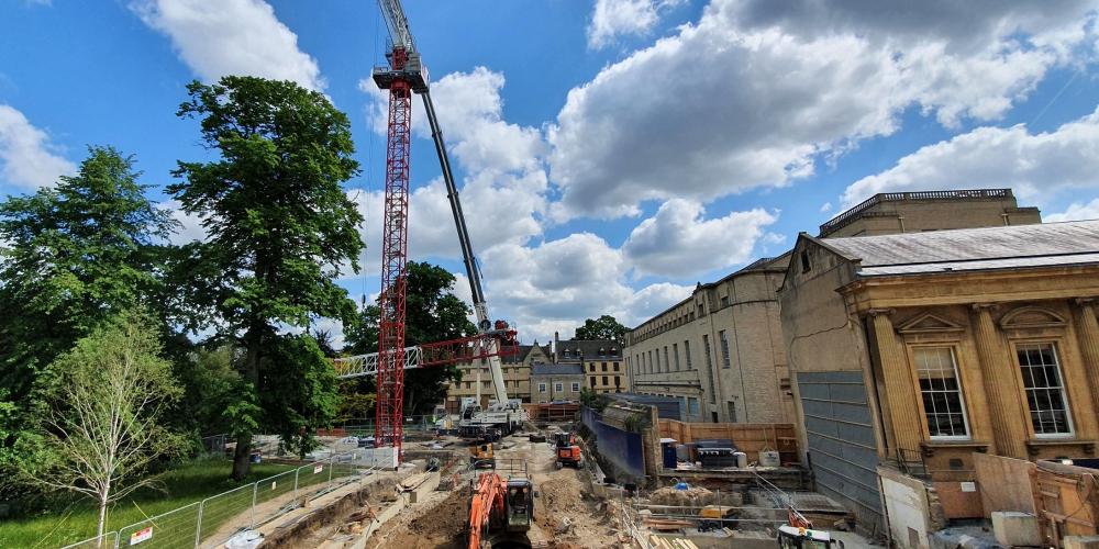 A wide angle view of the Levine Building site in August, with a giant crane and the Weston Library.