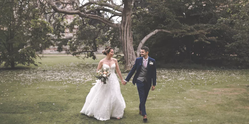 A wedding couple walks across the Trinity front quad.