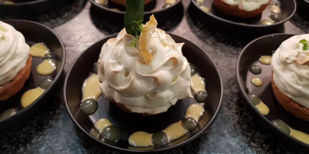 A tray of prepared baked Alaska lemon meringue pies.