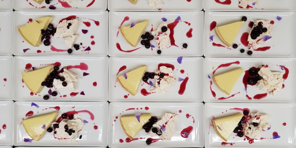 A dozen plates of lemon and white chocolate tart with pavlova, blueberry sorbet and compote.