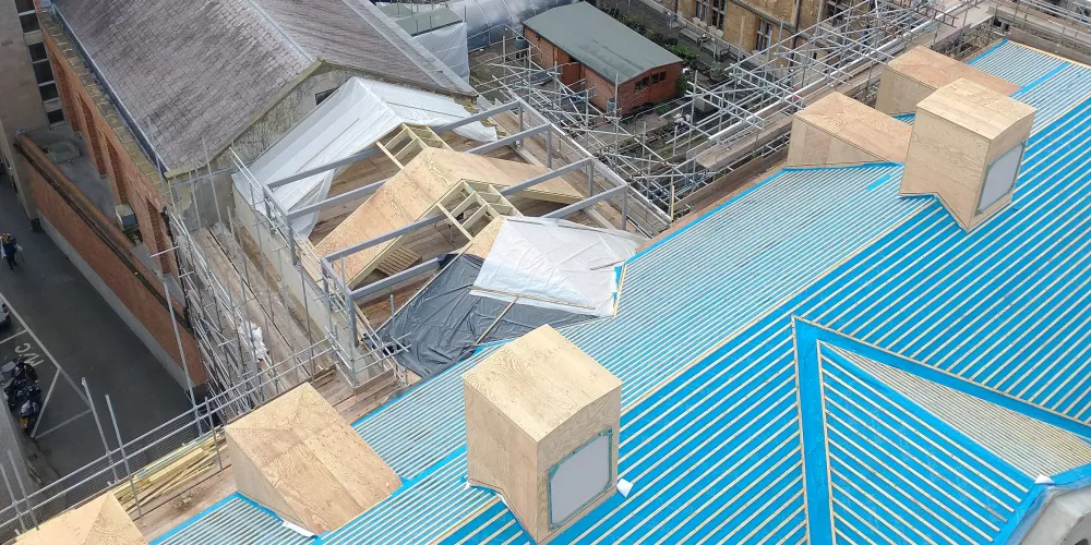 An aerial view of the roof of the Levine Building. It is covered in blue plastic sheeting.