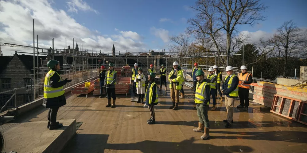 A group of Trinity staff and building site workers stand spaced out at the top of the Levine Building for the topping out.