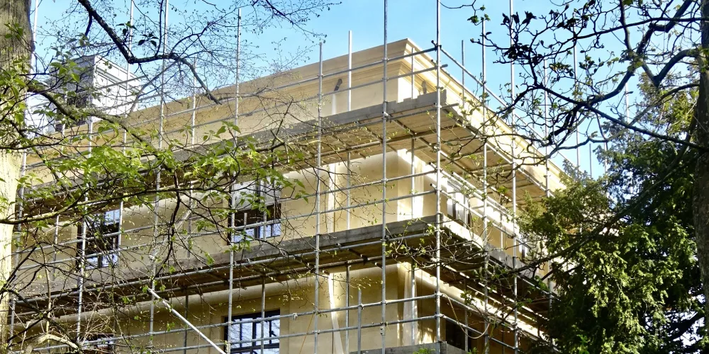 A view of the nearly complete Levine Building from the college wilderness; the scaffolding remains but the building exterior is near complete.