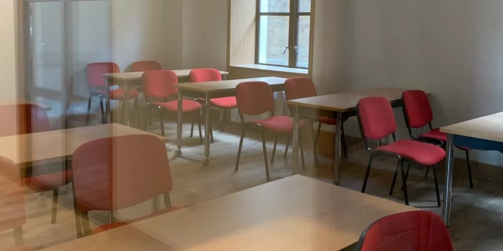 Inside a teaching room in the new Levine Building, with red chairs and wooden tables.