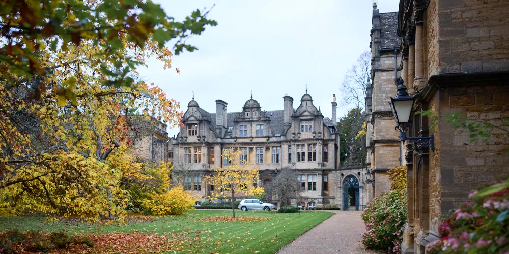 A view of the front quad, Jackson building and president's lodgings at Trinity in Autumn, with trees showing yellow and orange leaves.