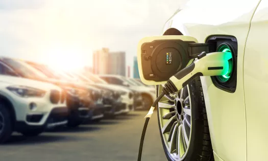 A white electric vehicle being charged in the foreground. 