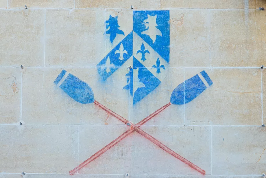 A chalked image of the Trinity College shield with boat club blades on the wall of a college building.