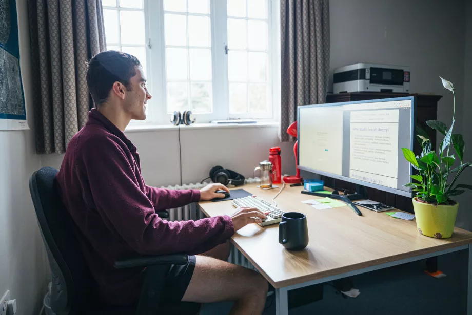 A postgraduate student sits studying at a desk. 