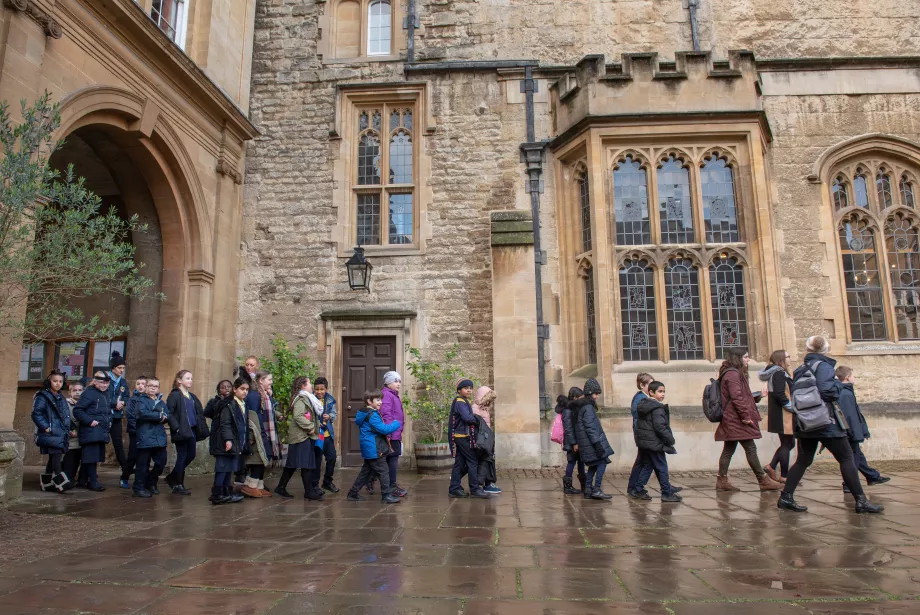 A group of primary school students walk in a line across Durham Quad on a visit to Trinity College.
