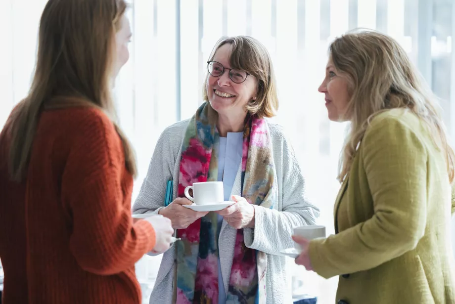 Trinity College President Hilary Boulding stands talking to a student and teacher at an access event.