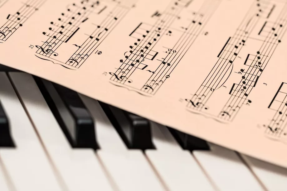 A piano keyboard with sheet music lying on top of it.