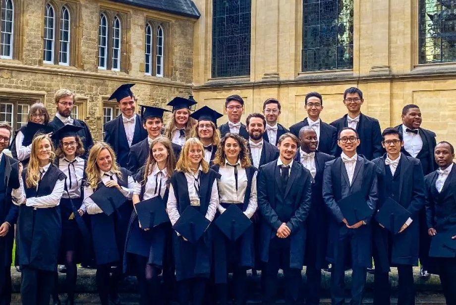 A matriculation photo of Trinity college postgraduates wearing sub-fusc clothing standing as a group in Durham Quad.