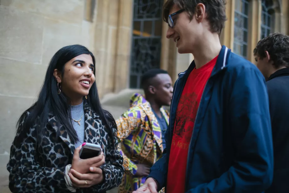 A female and male student stand chatting in Trinity college.