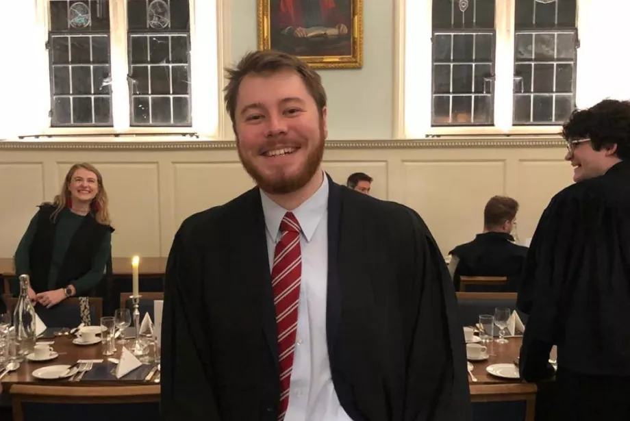 Thomas Cross stands at a table in the Trinity Dining Hall.